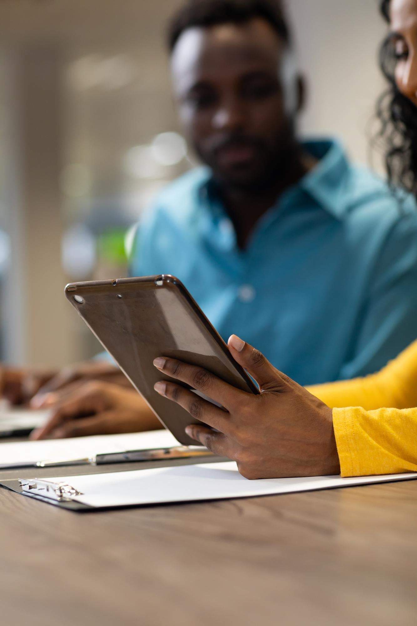 Colleagues at a meeting table, one holding a tablet